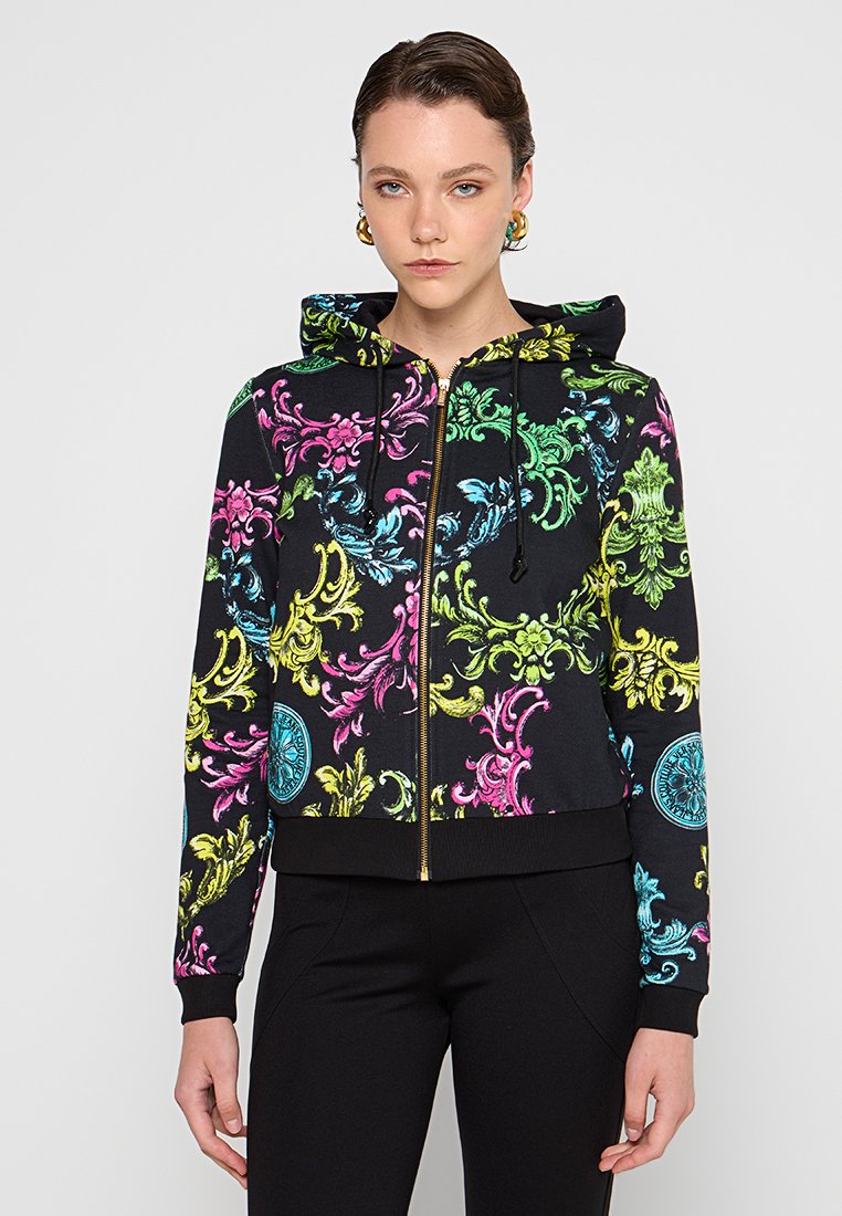 Czarna bluza z kapturem zapinana na zamek z kolorowymi, kwiatowymi wzorami w odcieniach różu, zieleni, żółci i niebieskiego. Materiał wydaje się być miękki, z kapturem ze sznurkiem i ściagaczami przy rękawach.
