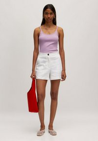 Lila tanktop, witte shorts met plooien aan de voorkant en een knoop, rode tote bag en lichtgrijze instappers. Glad textuur, moderne vorm.