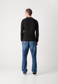 Svart langermet skjorte kombinert med lyseblå denimjeans. Jeansene har et klassisk fem-lommersdesign og en avslappet passform.