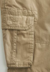 Pantaloni cargo beige in tessuto, dotati di una tasca laterale con patta, cuciture rinforzate e una superficie liscia.