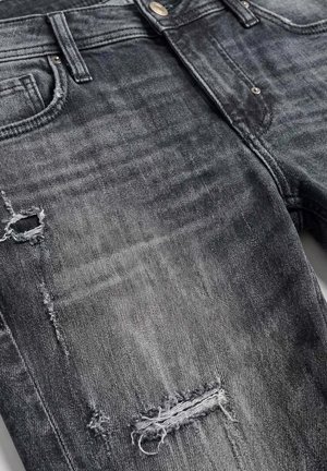 Jean en denim noir avec des détails usés et des trous effilochés au niveau des cuisses et des genoux, doté de poches avant et d'une fermeture à bouton.