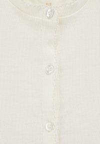 Kratak prikaz bijelog rebrastog materijala s tri bisernim dugmeta i suptilnim dekorativnim šavovima duž šava dugmeta.