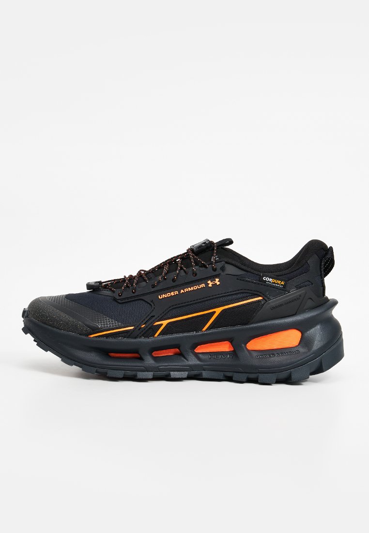 Zapatilla deportiva Under Armour negra y naranja con suela robusta, detalles reflectantes y sistema de cordones rápidos.