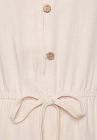 Abito beige chiaro con chiusura a bottoni, vita arricciata con fiocco legato e tessuto morbido e texture.