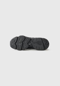 Black athletic shoe sole with textured rubber, featuring multi-directional tread patterns for grip and durability. Brand logo visible.