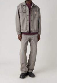 Chaqueta de denim gris con dos bolsillos en el pecho, combinada con pantalones grises a juego y zapatillas negras. La tela tiene una textura suave y un corte casual.