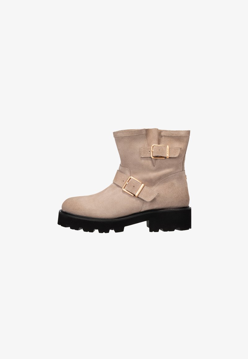 Stivale alla caviglia in suede beige con suola nera chunky e due cinturini regolabili in tonalità oro, chiusura con zip laterale.