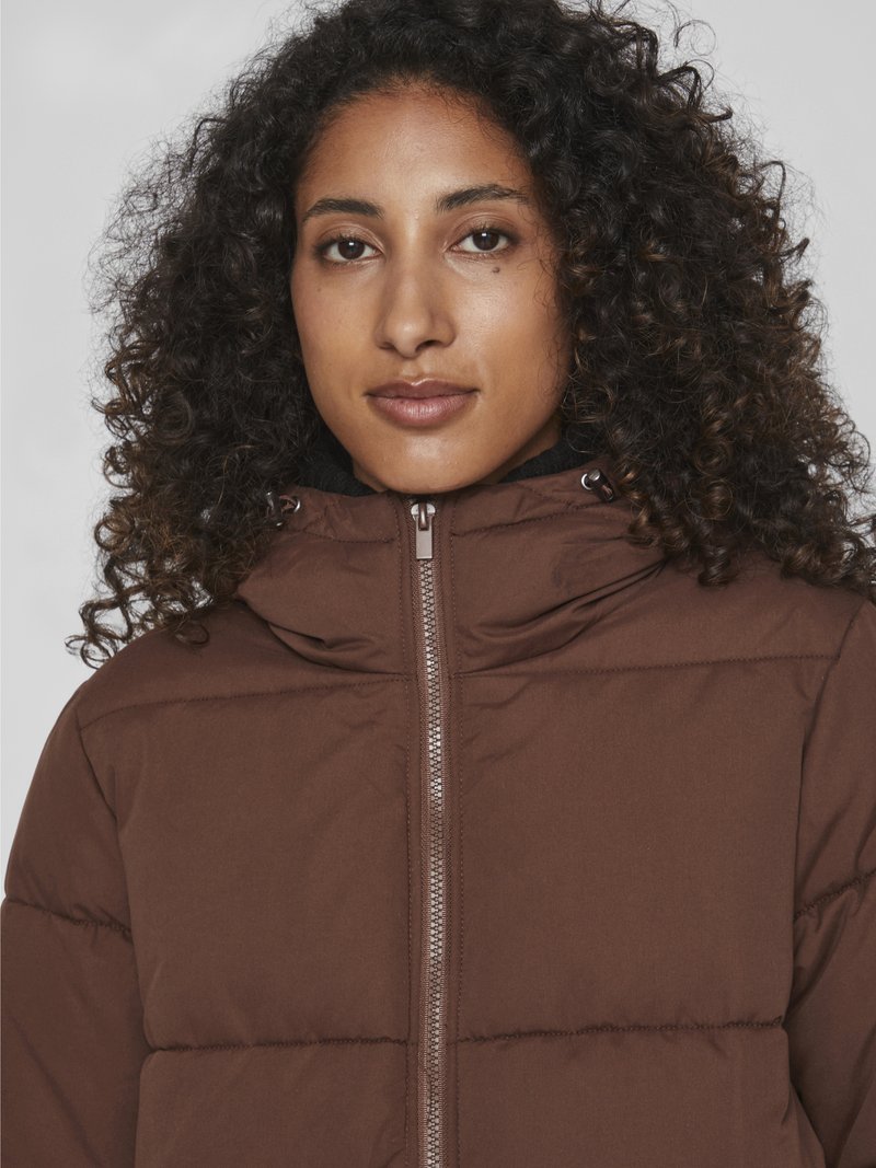 Braune Pufferjacke mit Reißverschluss, ausgestattet mit einem hohen Kragen und einer Kapuze. Der Stoff ist glatt mit einer gesteppte Textur, die Wärme und Komfort bietet.