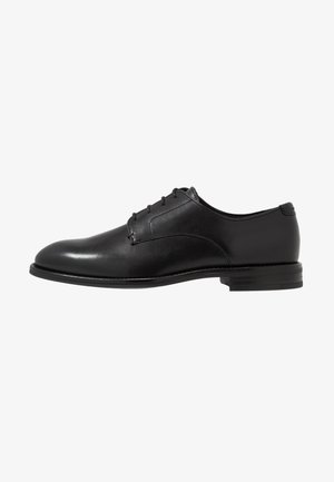 Sapato de couro preto com um acabamento suave, bico redondo, seis ilhós e um salto baixo empilhado. Design simples e clássico.