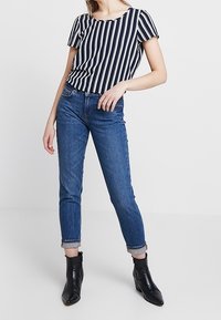 Navy en witte gestreepte blouse met korte mouwen gecombineerd met lichtblauwe skinny jeans met opgerolde randen en zwarte enkellaarsjes.