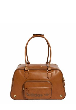 Sac de sport Adidas marron avec deux poignées supérieures, pièces métalliques dorées, poche zippée à l’avant et logo Adidas imprimé en noir sur la poche avant.