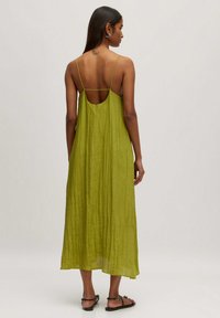 Grünes, ärmelloses Maxikleid mit einer gekräuselten Textur und einem offenen Rückendesign. Verfügt über dünne Träger und einen entspannten Schnitt, der bis zur Mitte der Waden reicht.