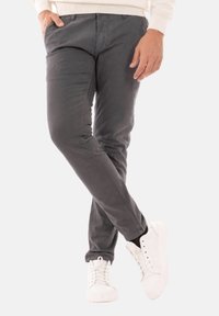 Pantaloni in cotone grigi con una vestibilità slim, dotati di tasche frontali e una texture liscia, abbinati a sneakers bianche.