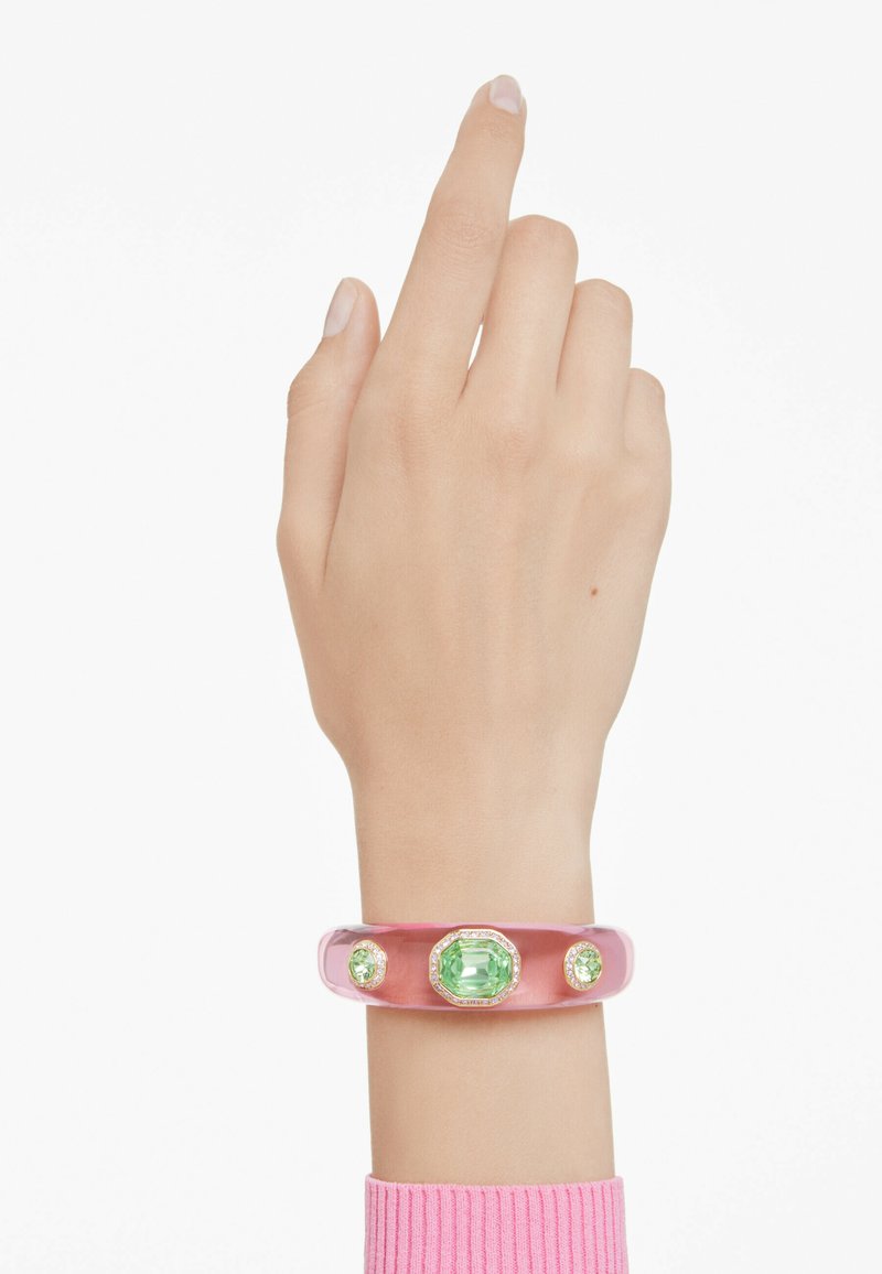 Translucent pink acrylic bracelet featuring three green gemstones, including an octagonal center stone and round accents. Smooth finish, modern design.