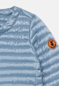 Lichtblauwe, gewatteerde pufferjack met een gladde, glanzende textuur en een oranje ronde patch met een eendgrafiek op de mouw.