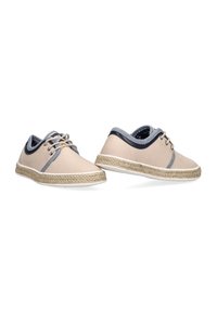 Zapatillas de lona beige con detalles en gris y suelas de yute trenzado. Punta redondeada, diseño con cordones y textura de forro interior en contraste.
