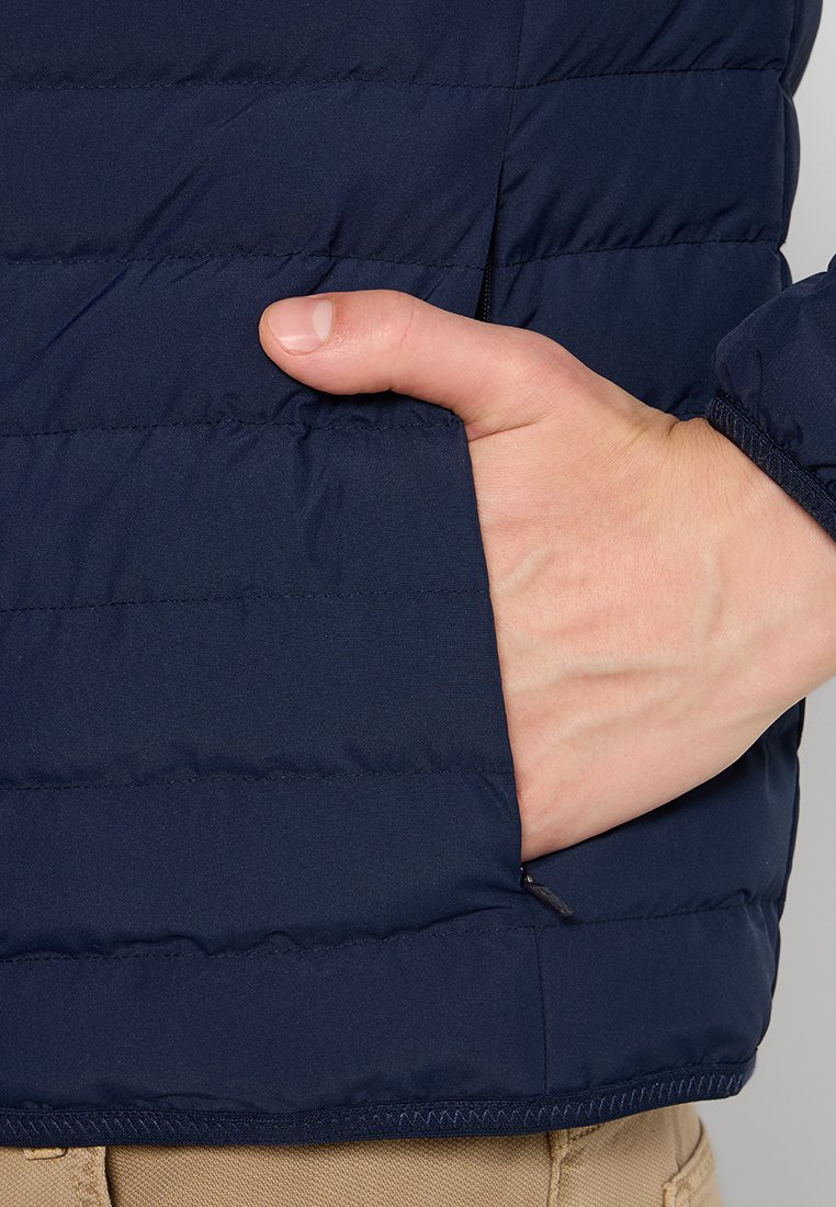 Doudoune bleu marine avec motif matelassé horizontal, dotée d'une poche latérale et de poignets élastiques. Textile doux et léger.