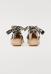 Svarte og beige espadrillosandaler med mønstrede stoffstropper, s�åle av jutevev og åpen bakt design. Stroppene har teksten "MADE".