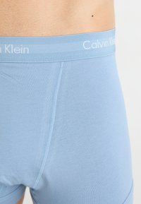 Világoskék pamut boxer alsónadrág, puha, rugalmas derékkal, amelyen a "Calvin Klein" logó szerepel. Sima textúra és testhezálló dizájn.