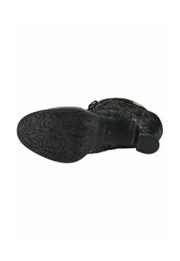 Suola di scarpa nera con texture e motivo floreale, dotata di un tacco robusto e marchio in rilievo, progettata per garantire aderenza e durabilità.