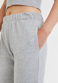 Hellgraue Sweatpants mit elastischem Bund und Seitentaschen, ausgestattet mit einer glatten Textur und einem entspannten Schnitt.