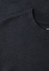 Pull en tricot gris foncé avec col rond côtelé et étiquette de vêtement visible à l'intérieur du col au dos.