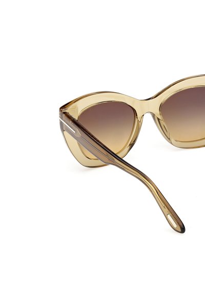Sluneční brýle ve stylu kočičích očí s průhledným jantarovým rámem, gradientními hnědými skly a štíhlými nohami se stříbrnými akcenty. Hladký povrch po celém obvodu.
