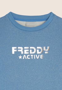 Felpa azzurro chiaro con una texture glitterata. Presenta una scollatura tonda e la scritta "FREDDY ACTIVE" in stampa metallizzata argento.