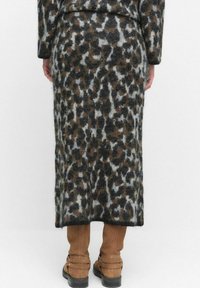 Leopardmönstrad midikjol i mjukt, texturerat tyg, med nyanser av grått, brunt och svart. Bärs med ljusbruna stövlar över knäna.