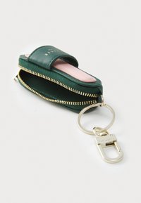 Green leather keychain wallet with a zip closure, pink interior, gold hardware, and a detachable clip for easy attachment to bags.