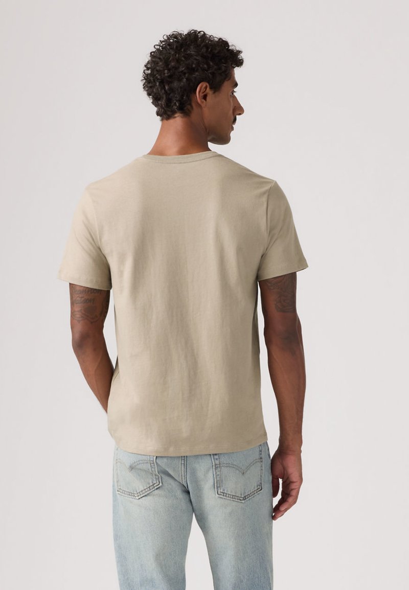 Beige bomulls-t-shirt med rund hals, korta ärmar och en avslappnad passform. Tyget är mjukt med en subtil textur och utan synliga mönster.