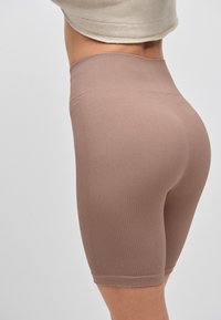 Högmidjade, ribbade shorts i ljusbrunt tyg. Har en tajt passform och når midt på låret, med en slät yta utan synliga detaljer.