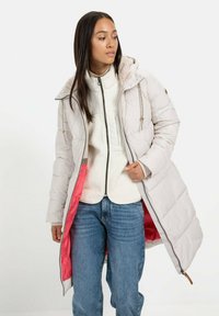 Helle graue, puffy lange Jacke mit einem mit Fell gefütterten Kapuze, pinkem Innenfutter, Reißverschluss vorne und elastischen Kordelzügen zur Anpassung.