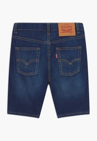 Pantaloni shorts in denim blu scuro, con vita alta, due tasche posteriori con cuciture distintive e un'etichetta in pelle marrone del marchio sul retro.