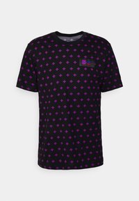 Camiseta negra de manga corta con un patrón de cruces moradas y azules en repetición. Presenta un pequeño parche de logo con el emblema del club y la marca.