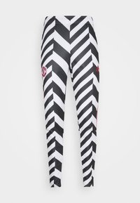 Svartvita leggings med zigzag-mönster för sport, med röd Manchester United-logotyp på vänster lår och röd Adidas-logotyp på höger lår.