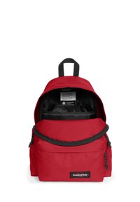 Punainen Eastpak-reppu, jolla on pyöristetty muoto, valmistettu kestävästä kankaasta. Varustettu etuosan vetoketjullisella taskulla, yläkahvalla ja säädettävillä olkahihnoilla. Sisäpinnalla musta vuorikangas.