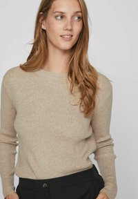 Pulover bej din tricot cu model în dungi, cu mâneci lungi și decolteu rotund, asortat cu pantaloni negri cu un detaliu de singur buton.