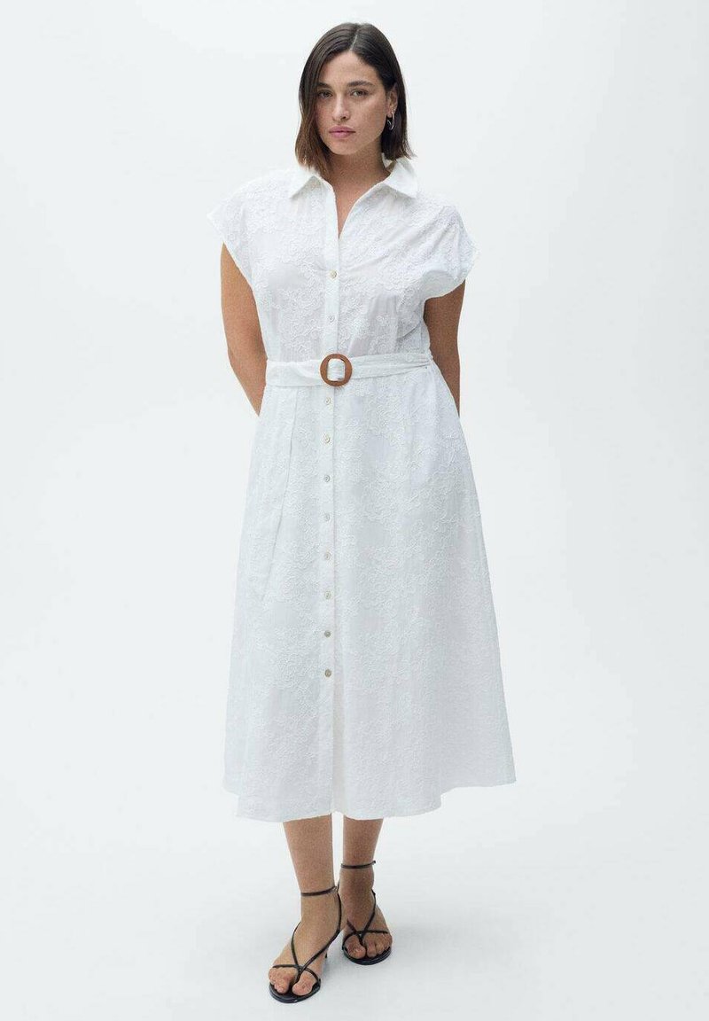 Abito camicia bianco con maniche corte, chiusura a bottoni sul davanti, cintura in vita con fibbia in legno e texture in pizzo. Design fino al ginocchio.