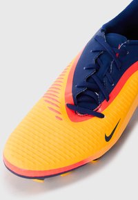 Chrono de football Nike en orange vif et bleu marine, avec un dessus texturé, des accents rouges contrastants et un système de laçage élaboré pour un meilleur support.