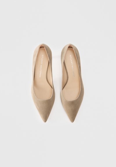 Beige suede high-heeled pumps with a pointed toe and a smooth interior. Features a subtle logo on the insole. Minimalist design.