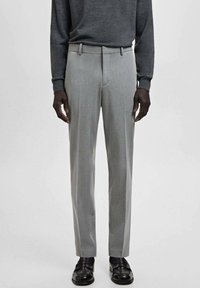 Jasnoszare, dopasowane spodnie o gładkiej fakturze, z płaskim przodem i szlufkami na pasek, w zestawieniu z ciemnym swetrem i czarnymi butami.
