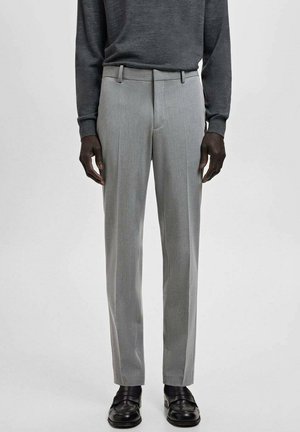 Jasnoszare, dopasowane spodnie o gładkiej fakturze, z płaskim przodem i szlufkami na pasek, w zestawieniu z ciemnym swetrem i czarnymi butami.