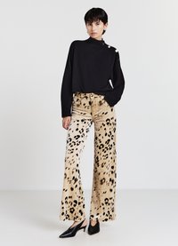 Schwarzer, kurzer Pullover mit hohem Kragen und drei Knöpfen an der Schulter; weite Leopardenmuster-Hose; schwarze spitze Absatzschuhe.