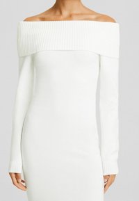 Vit off-shoulder klänning med långa ärmar. Ribbad halsringning och manschetter, mjukt, lätt tyg, figurnära design.