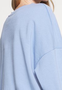 Ljusblå sweatshirt med lös passform och mjuk textur, rundad halsringning och sänkta axelsömmar för extra komfort.
