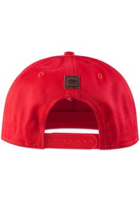 Red baseball cap with a flat brim, adjustable plastic strap at the back, and a small square patch labeled "MSTRDS MUNICH." Smooth fabric texture.