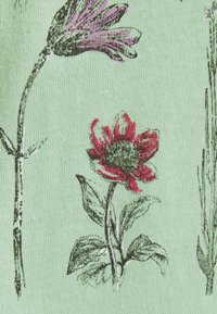 Tissu en coton vert pâle avec des imprimés floraux ; présente une fleur rouge et une fleur violette délicatement esquissées avec des contours noirs et des accents verts.