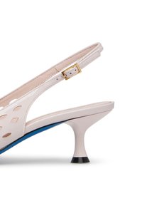 Décolleté slingback in vernice rosa pallido con ritagli geometrici, tacco medio e suola blu a contrasto con punta nera.