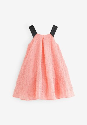 Pfirsichfarbenes Spitzenkleid mit strukturiertem Muster, schwarzen Trägern, ausgestelltem Schnitt und subtilen Falten im Oberteil.
